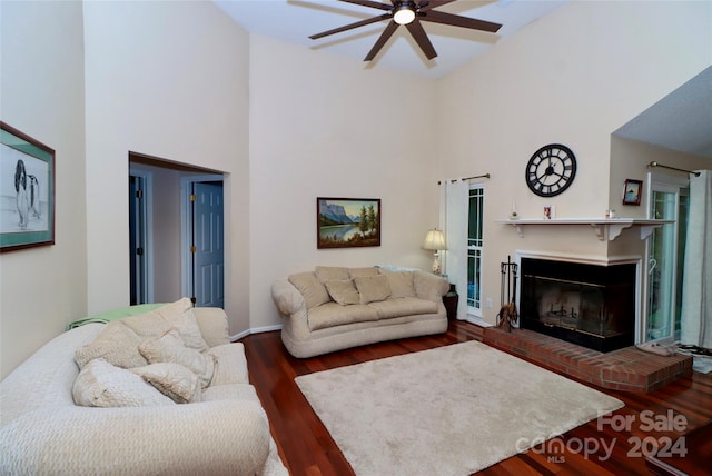 living room featuring a towering ceiling, a fireplace, dark wood-type flooring, and ceiling fan