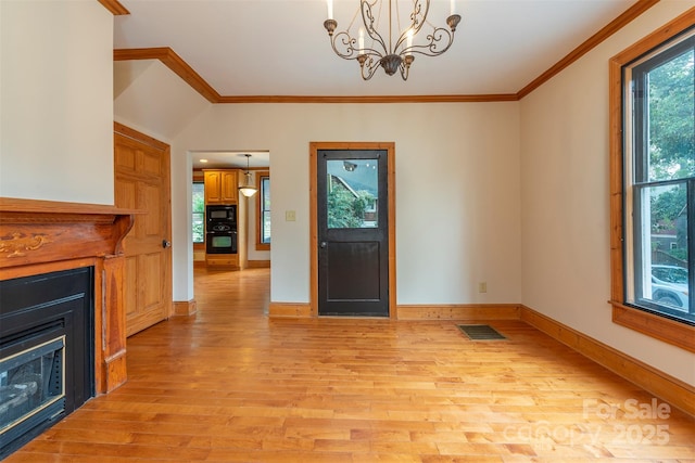 interior space featuring light wood finished floors, a fireplace, visible vents, and crown molding