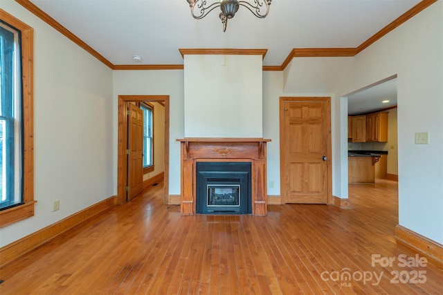 unfurnished living room featuring ornamental molding, a fireplace with flush hearth, light wood-style flooring, and baseboards