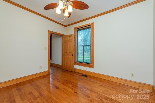 unfurnished room featuring wood finished floors, a ceiling fan, baseboards, visible vents, and crown molding