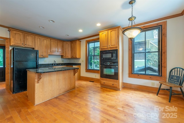 kitchen with black appliances, hanging light fixtures, dark stone countertops, and crown molding