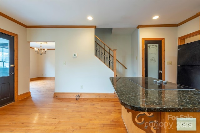 kitchen with black appliances, light wood finished floors, and crown molding