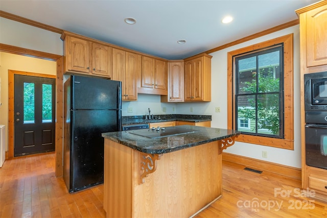 kitchen featuring a kitchen island, visible vents, a kitchen breakfast bar, black appliances, and dark stone countertops