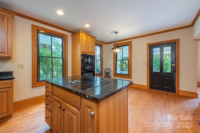 kitchen featuring a kitchen island, light wood-style floors, a healthy amount of sunlight, black appliances, and crown molding