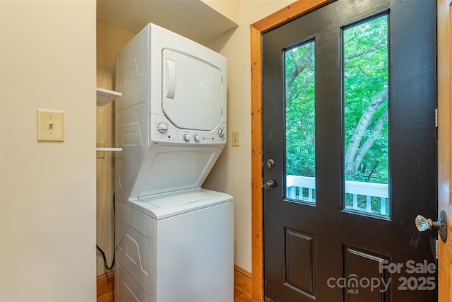 clothes washing area with stacked washer and clothes dryer and laundry area