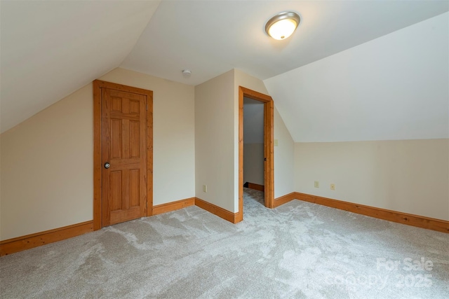 additional living space with lofted ceiling, light carpet, and baseboards