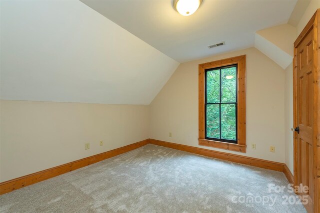 additional living space with carpet floors, lofted ceiling, visible vents, and baseboards