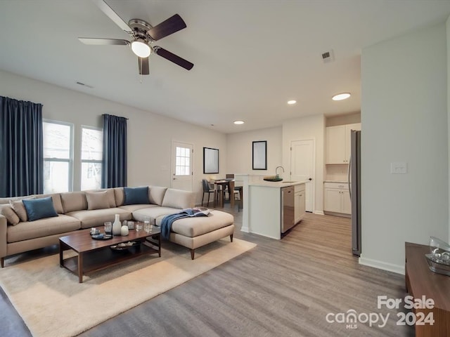 living room featuring light hardwood / wood-style flooring, ceiling fan, and sink