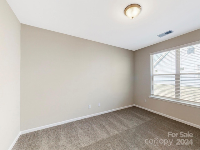 empty room with baseboards, visible vents, and carpet flooring