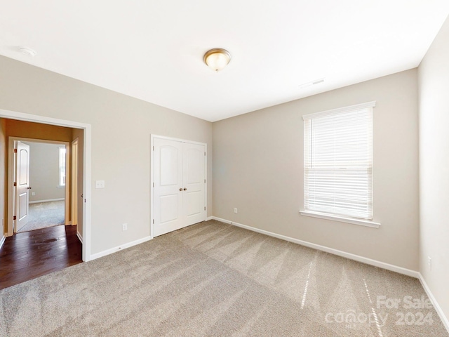 unfurnished bedroom with visible vents, a closet, baseboards, and carpet flooring