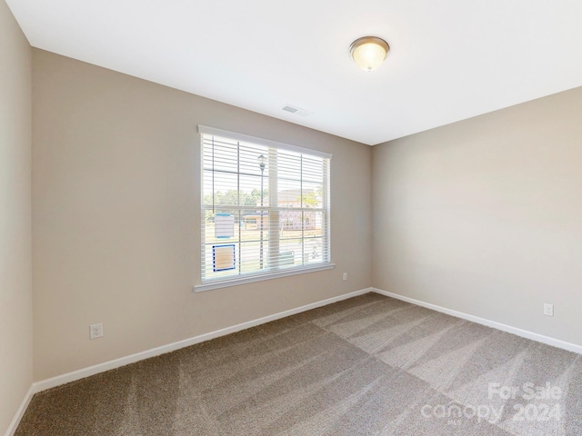 carpeted spare room featuring visible vents and baseboards