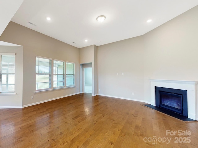 unfurnished living room featuring visible vents, a fireplace, baseboards, and wood finished floors