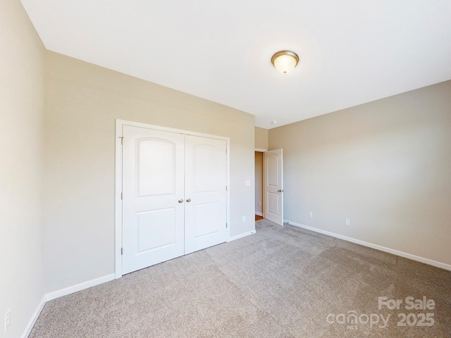 unfurnished bedroom featuring light colored carpet and a closet