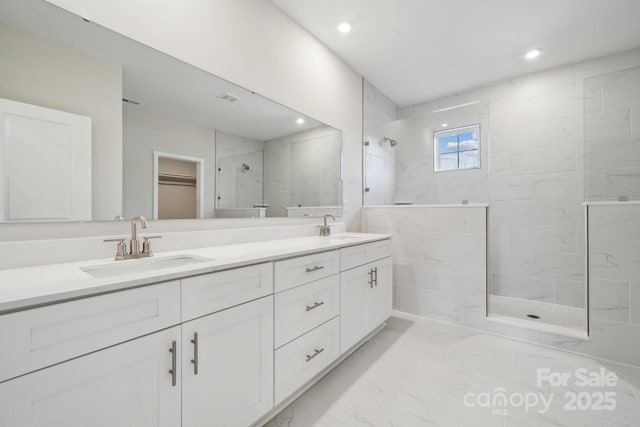 bathroom featuring a tile shower and vanity