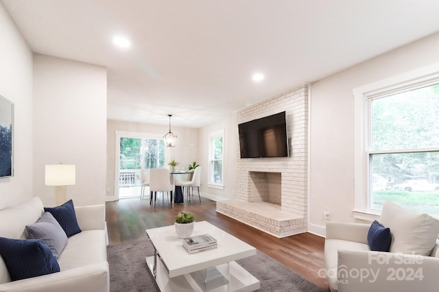 living room with an inviting chandelier, dark hardwood / wood-style flooring, and a fireplace