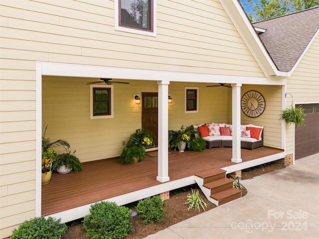 wooden terrace with outdoor lounge area, a garage, ceiling fan, and a porch