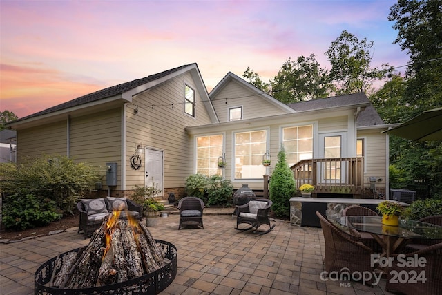 back house at dusk with a fire pit and a patio