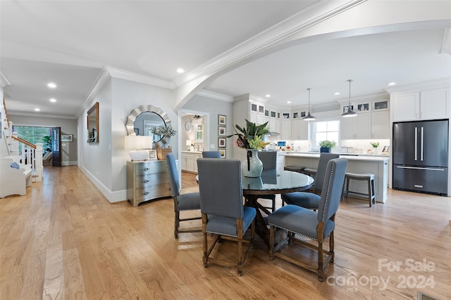 dining space featuring ornamental molding and light wood-type flooring