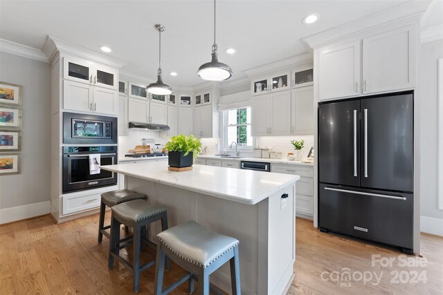 kitchen with a kitchen island, stainless steel appliances, white cabinetry, and light hardwood / wood-style flooring