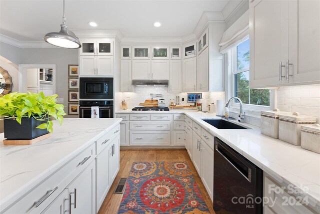 kitchen with light hardwood / wood-style flooring, black appliances, light stone counters, sink, and white cabinets