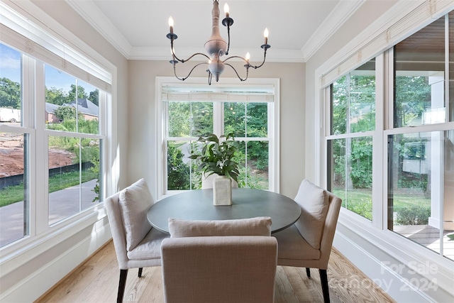 dining space with a wealth of natural light, light hardwood / wood-style flooring, ornamental molding, and a chandelier