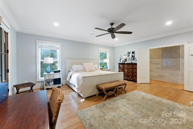 bedroom featuring ceiling fan, ornamental molding, light wood-type flooring, and multiple windows