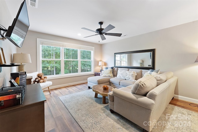 living room featuring baseboards, ceiling fan, visible vents, and wood finished floors