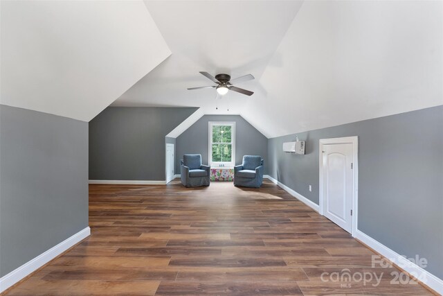 additional living space featuring dark wood-type flooring, ceiling fan, a wall unit AC, and vaulted ceiling