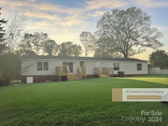 back house at dusk with a yard and central air condition unit