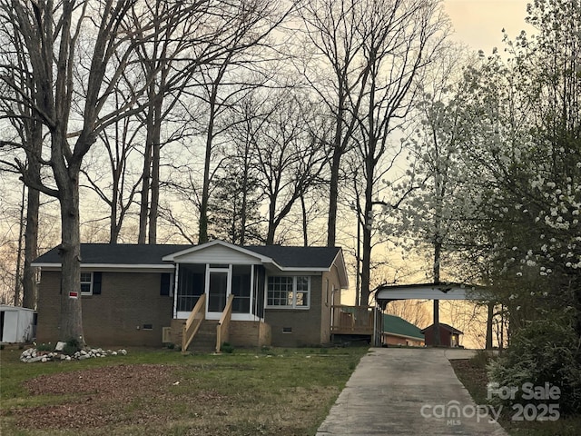 view of front facade with concrete driveway, a front yard, a sunroom, crawl space, and a carport