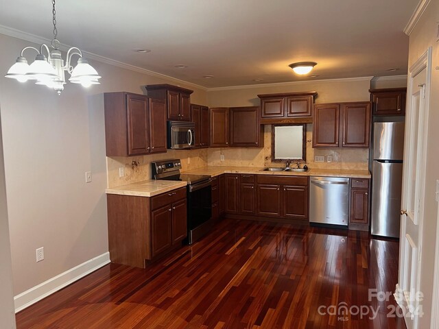 kitchen featuring crown molding, dark wood finished floors, light countertops, stainless steel appliances, and a sink