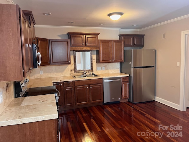 kitchen featuring a sink, light countertops, ornamental molding, appliances with stainless steel finishes, and dark wood-style flooring