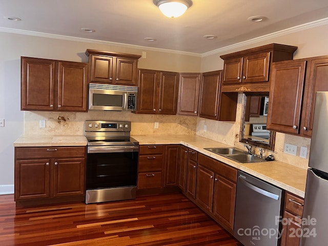 kitchen featuring crown molding, light countertops, appliances with stainless steel finishes, dark wood-style floors, and a sink