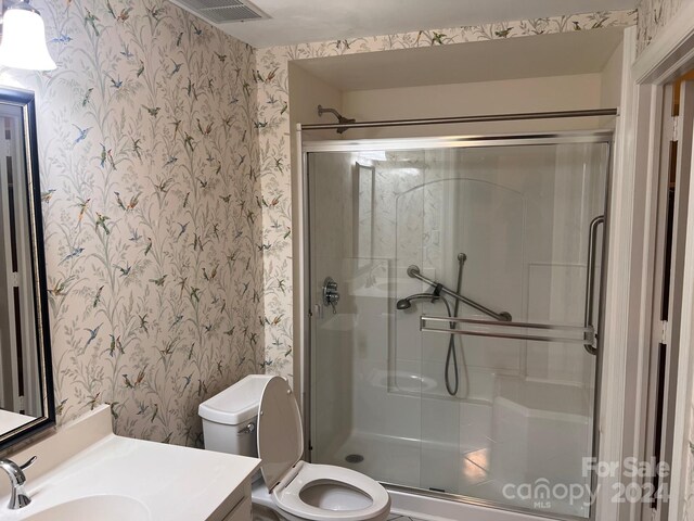 bathroom featuring vanity, toilet, and an enclosed shower