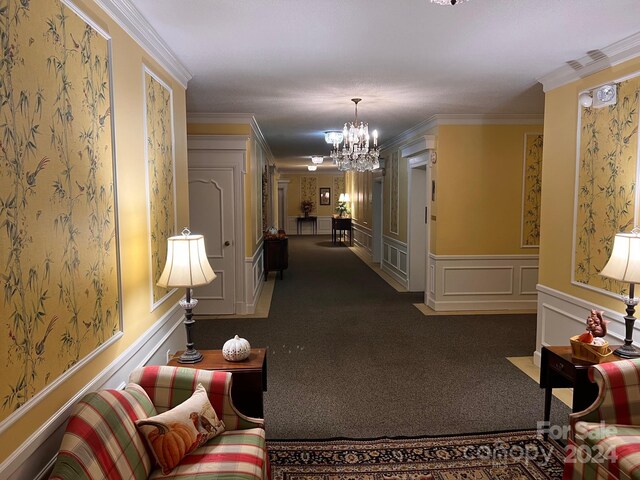 hall with a decorative wall, wainscoting, crown molding, and an inviting chandelier