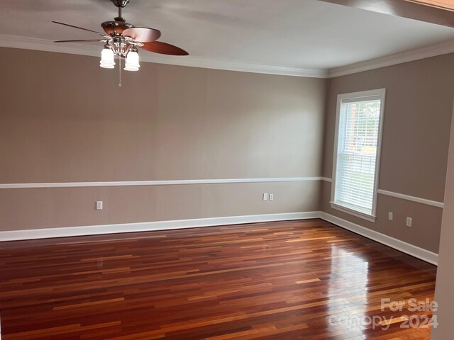 empty room with a ceiling fan, wood finished floors, baseboards, and ornamental molding