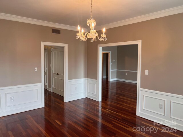 spare room with ornamental molding, dark hardwood / wood-style flooring, and an inviting chandelier