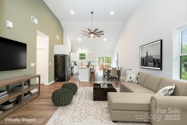 living room featuring ceiling fan, high vaulted ceiling, and light hardwood / wood-style floors