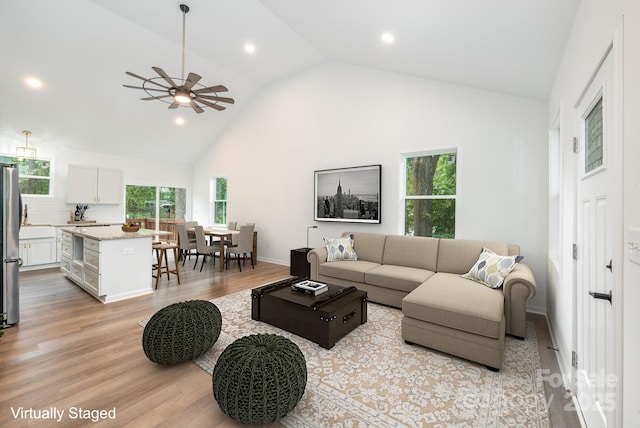 living room featuring ceiling fan, light hardwood / wood-style flooring, and high vaulted ceiling