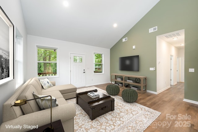 living room featuring high vaulted ceiling, light wood-type flooring, and a wealth of natural light