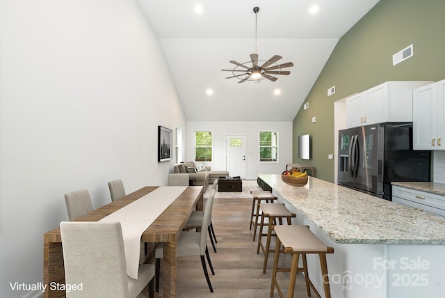 dining area featuring hardwood / wood-style flooring, ceiling fan, and high vaulted ceiling