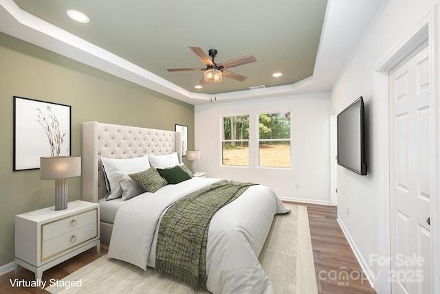 bedroom featuring a tray ceiling, ceiling fan, and light hardwood / wood-style floors