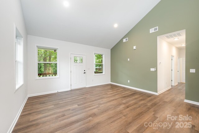 spare room featuring high vaulted ceiling, light wood-type flooring, and a wealth of natural light