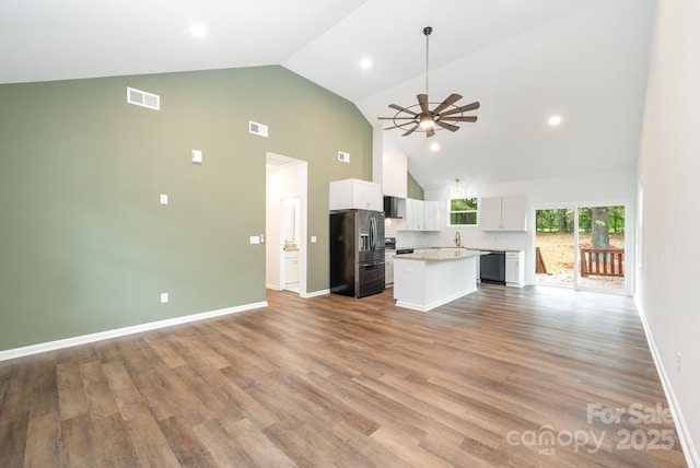 kitchen featuring black dishwasher, a kitchen island, stainless steel fridge, decorative backsplash, and white cabinets