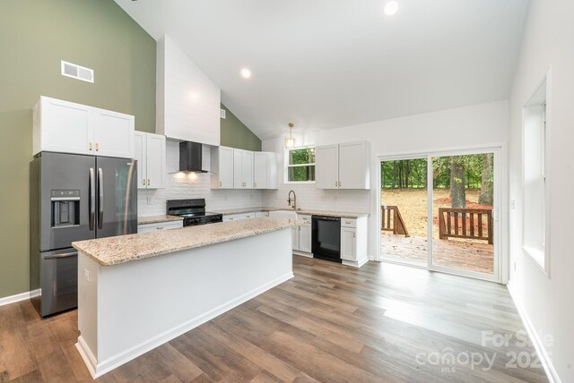 kitchen featuring black appliances, a kitchen island, wall chimney range hood, light stone countertops, and white cabinets