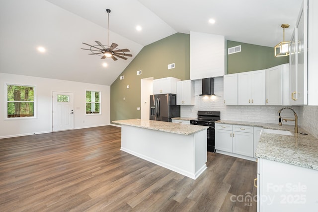 kitchen featuring a center island, wall chimney range hood, stainless steel fridge with ice dispenser, black range with gas cooktop, and white cabinets