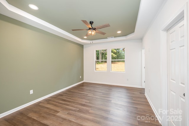 unfurnished bedroom with hardwood / wood-style flooring, ceiling fan, and a tray ceiling