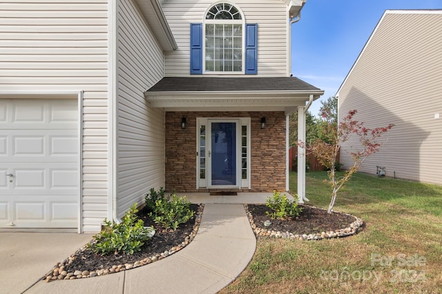 doorway to property with a lawn, covered porch, and a garage