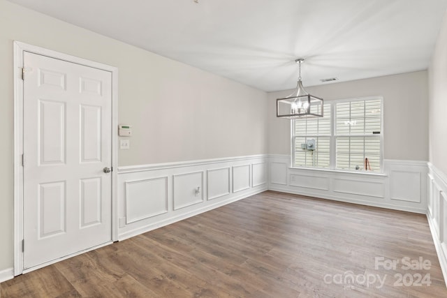 unfurnished dining area featuring wood-type flooring and a chandelier