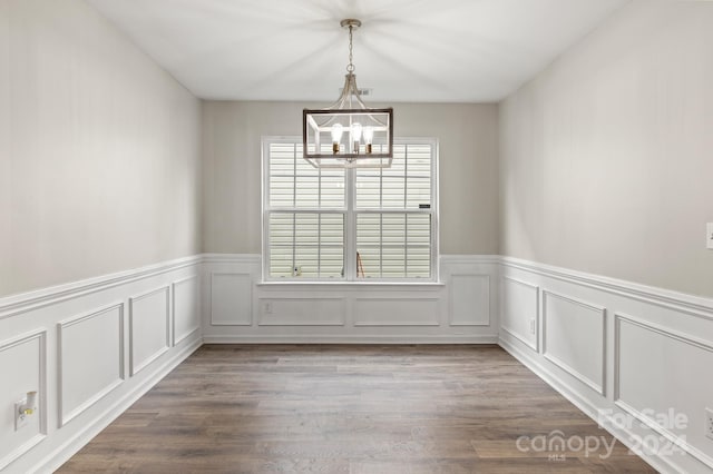 unfurnished dining area featuring a chandelier and hardwood / wood-style flooring